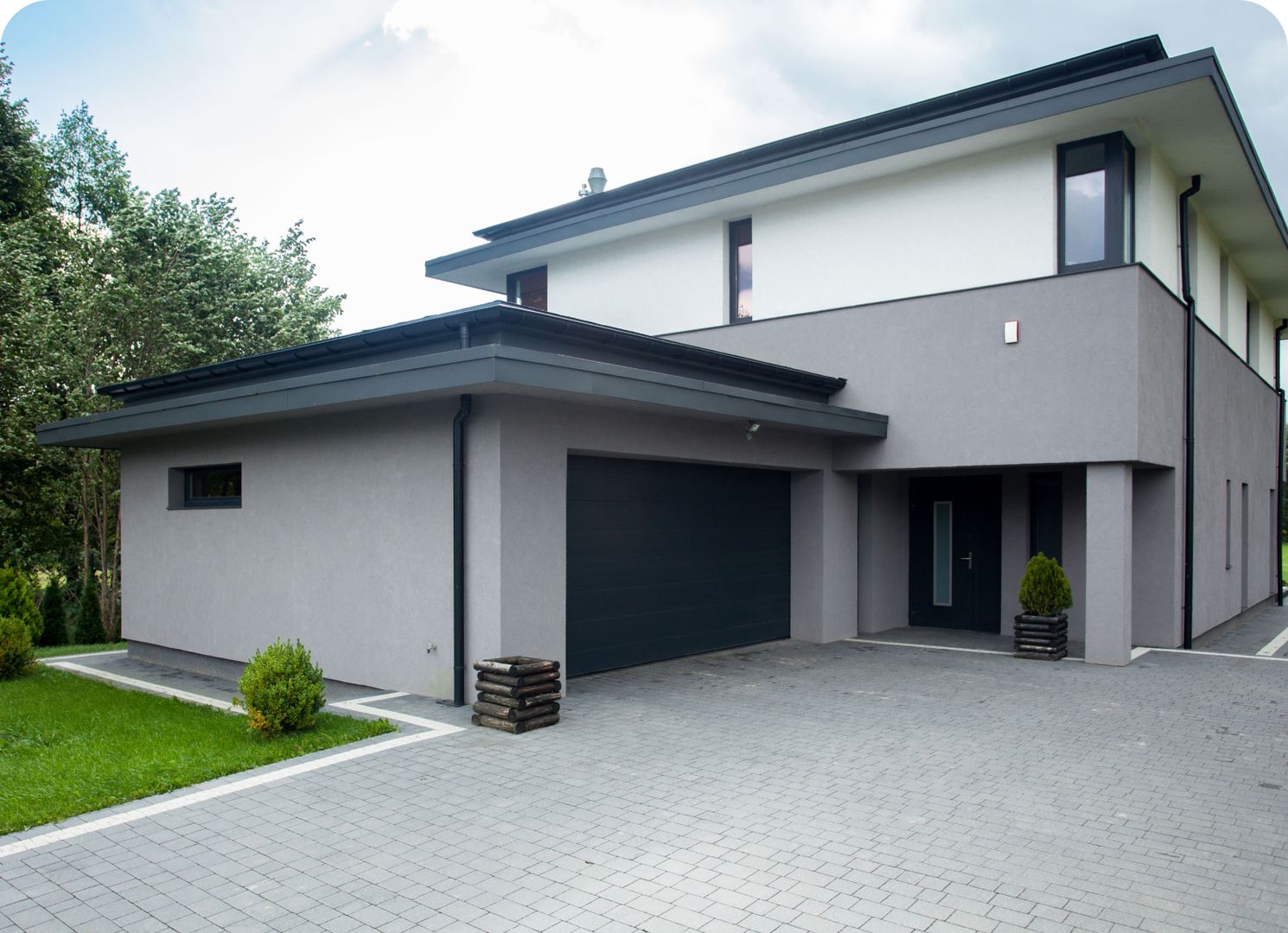 Modernes Einfamilienhaus mit gepflasterter Einfahrt und einem Garagen-Sektionaltor